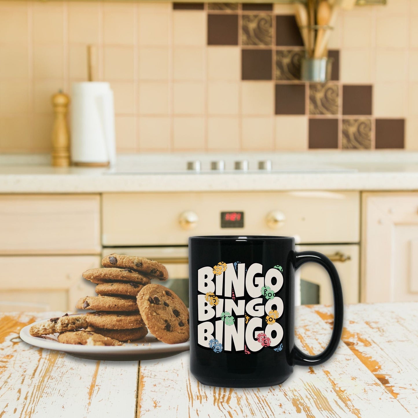 a black coffee mug sitting next to a plate of cookies