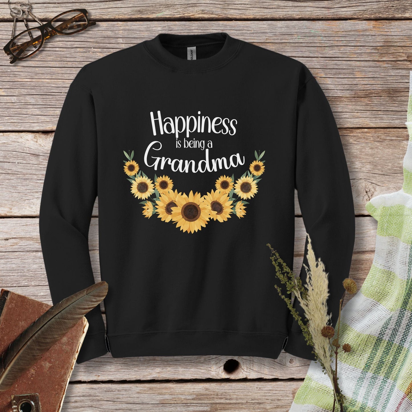 a black sweatshirt with sunflowers that says happiness is being a grandma