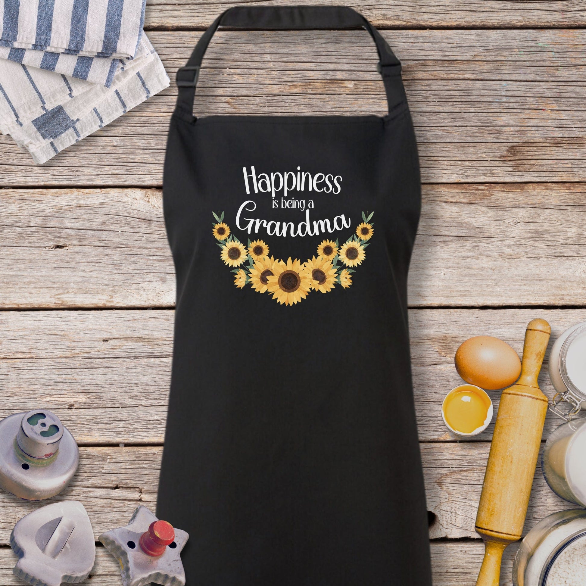 a black apron with sunflowers and the words happiness is in grandma