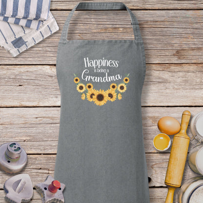 a gray apron with sunflowers and the words happiness is being grandma on it