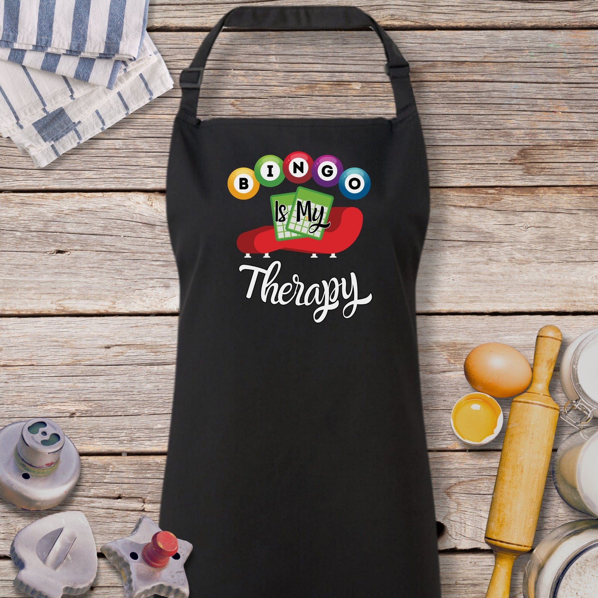 a black apron that says boo is my therapy