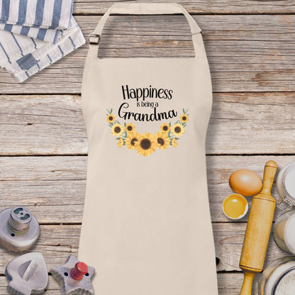 a white apron with sunflowers and the words happiness is being grandma on it