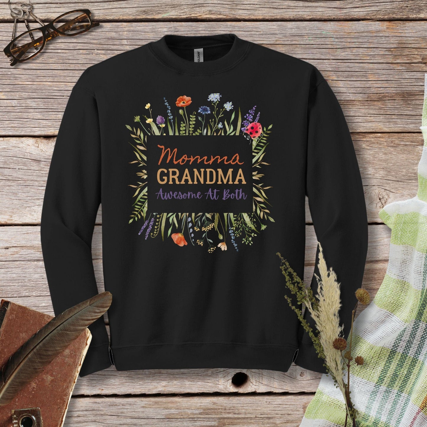 a black sweatshirt with the words momma of a grandma surrounded by flowers